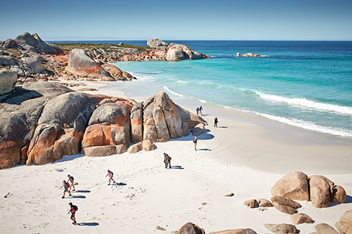 Ariel view of beach, sand and rocks with people walking along the sand