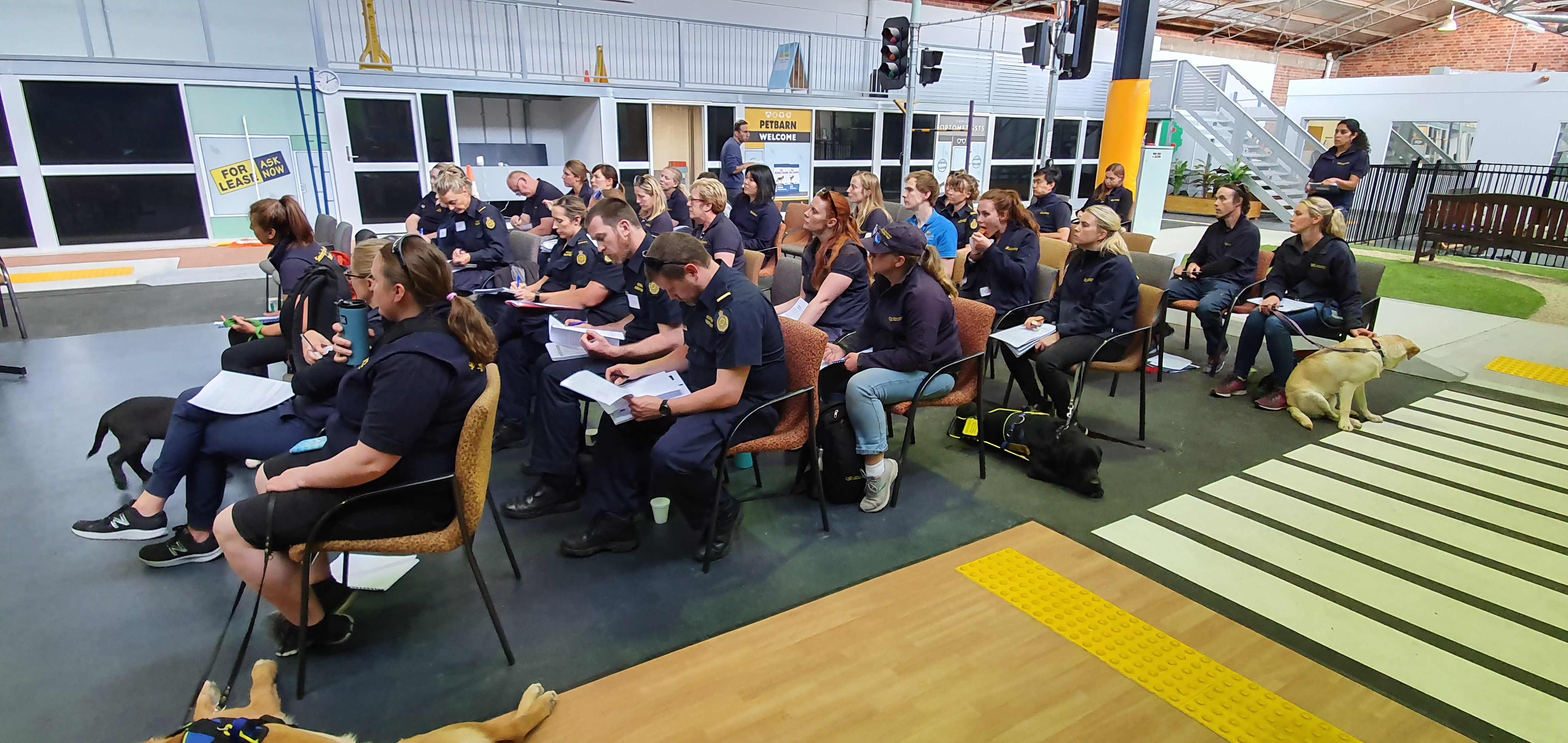 Attendees sitting, looking at notes in the Mobility Training Centre while Jane Russenberger leads a lecture.