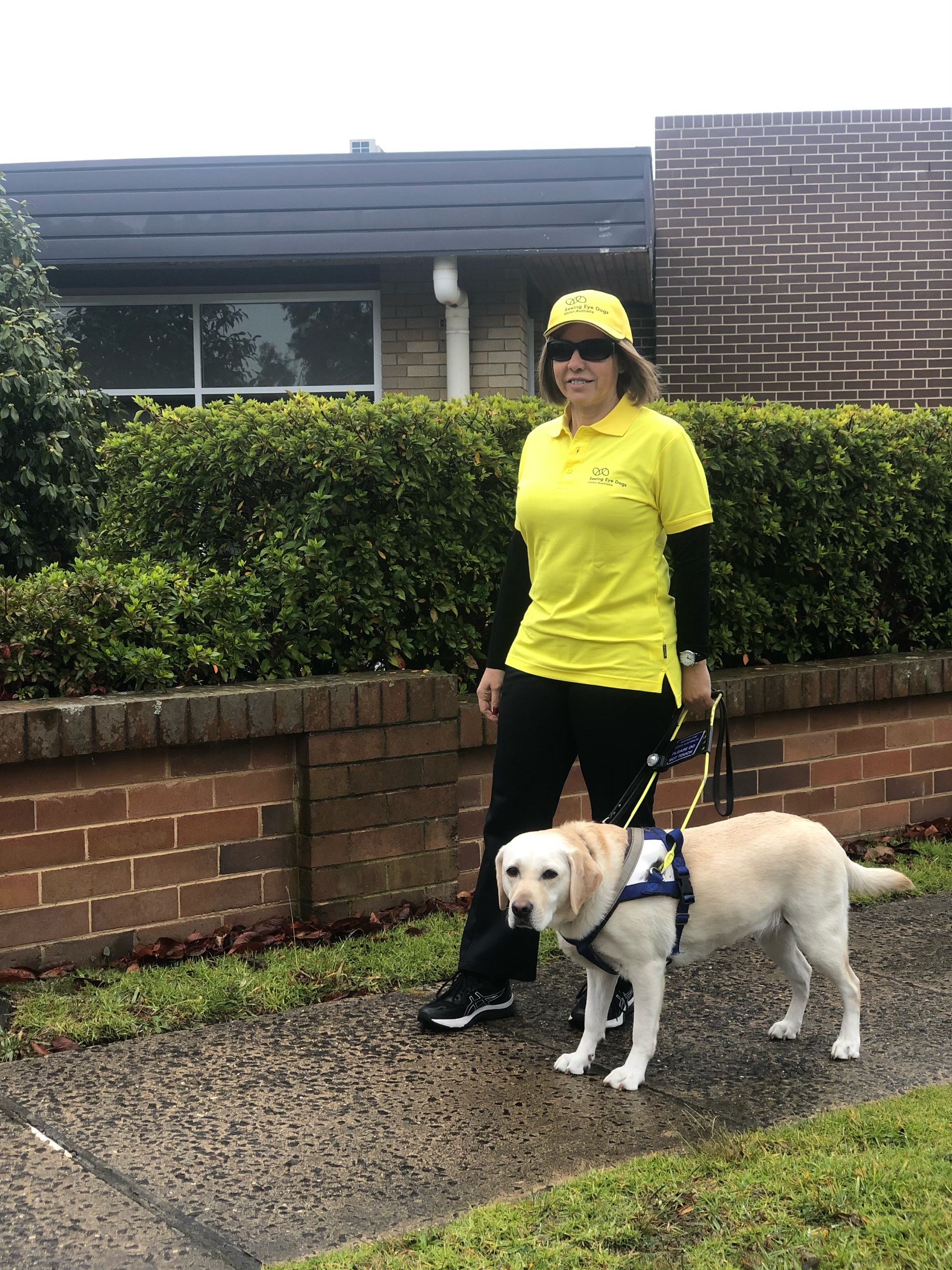 Lucia and Aura stand on a suburban street, Lucia in fluro jacket on an overcast day.