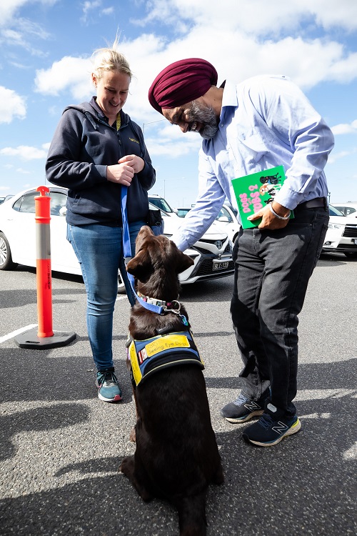 A man and woman stand outside with a Seeing Eye Dog in training